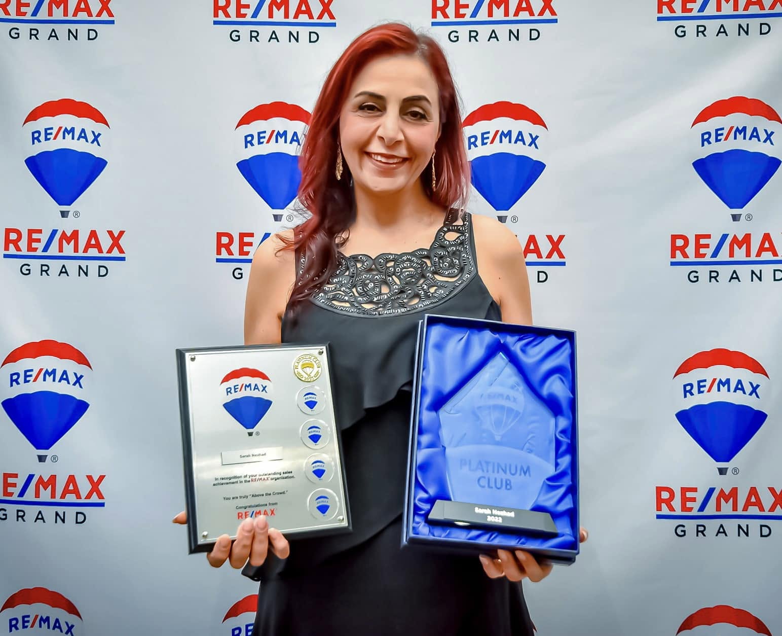 Sarah Nezhad holding her RE/MAX Platinum Club award